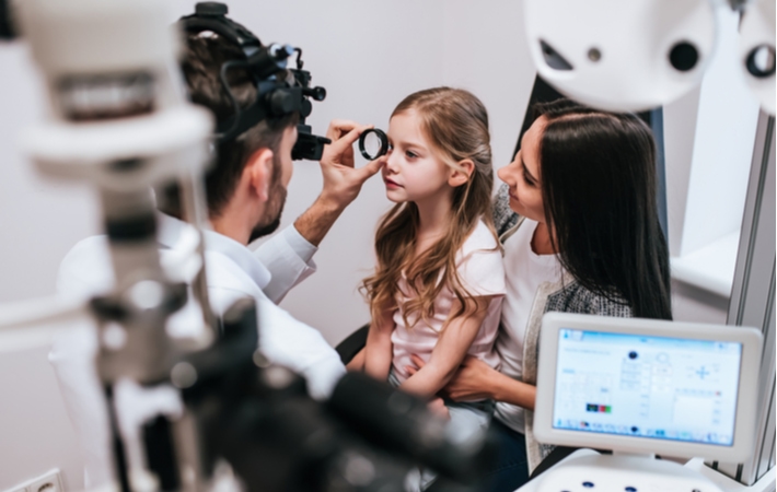 A young girl at the optometrist getting checked for myopia to manage it as early as possible