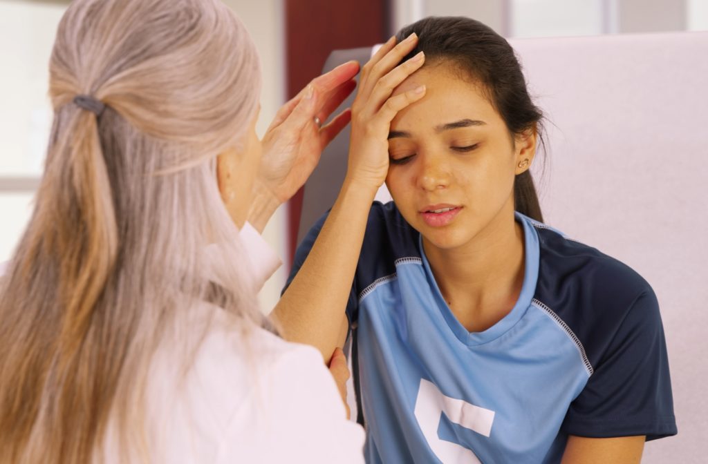 A young girl in her soccer uniform getting assessed after suffering a concussion