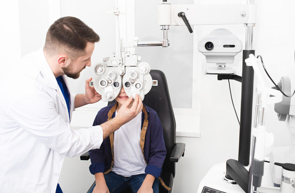 A male optometrist is using Phoropter to check a boy's eye health and visual acuity and refractive error.