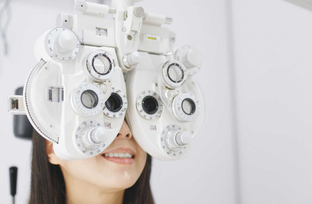 A patient looking through a phoropter during an eye exam to have their eyes examined for myopia or astigmatism