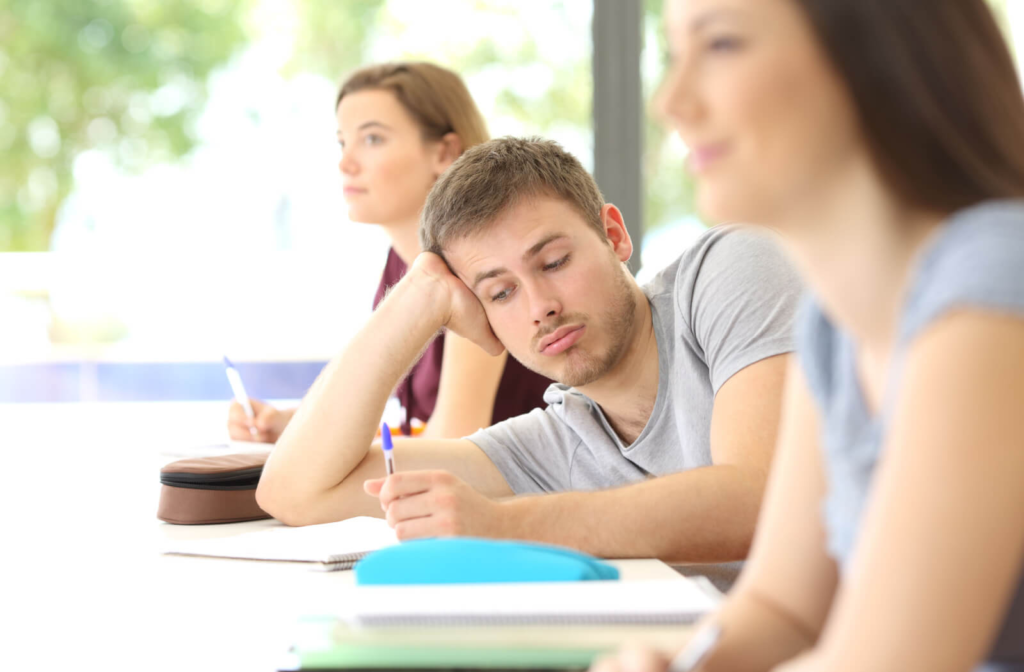 A student in the middle of two other students having a difficult time concentrating, listening, and participating in class.