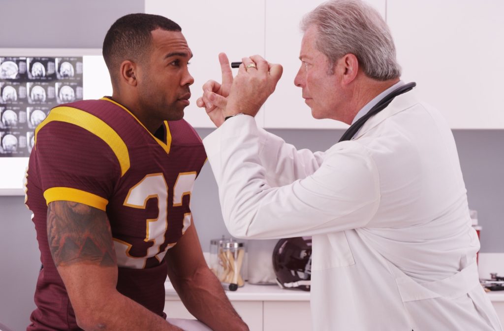 A foot ball player being checked by his eye doctor for concussion symptoms.