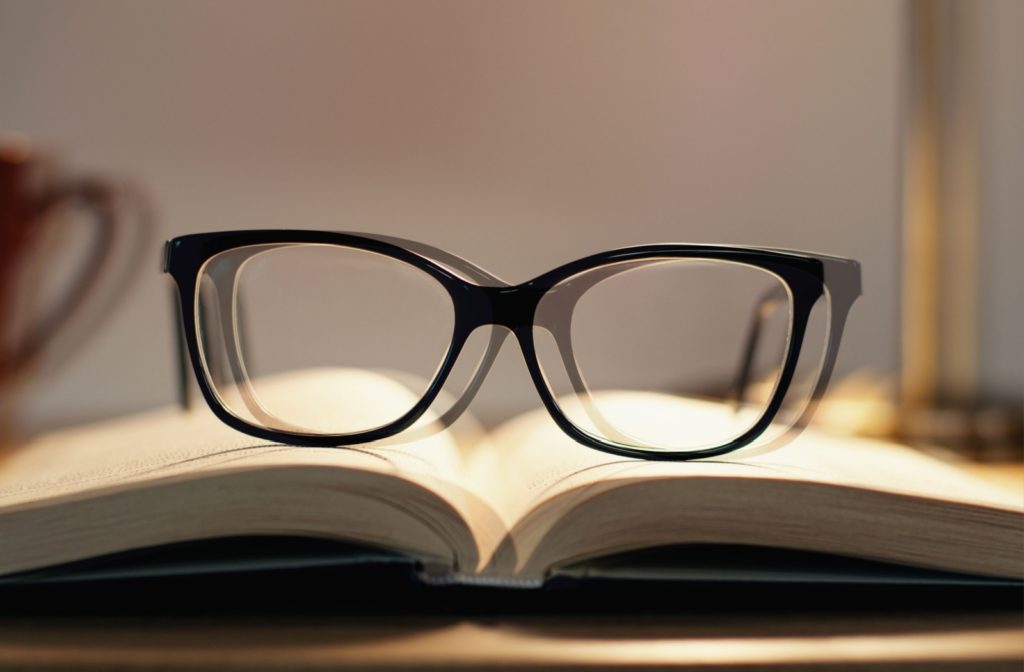 A point of view of someone with double vision looking at a pair of glasses on an opened book.