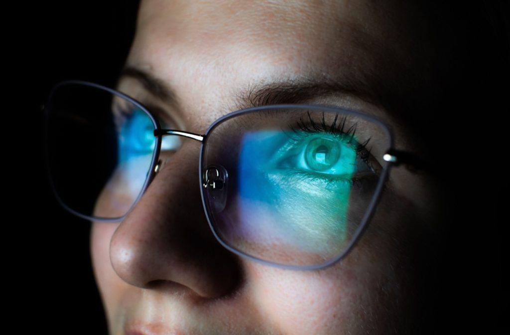 A woman wearing blue light glasses to block harmful LED light from her digital screen.