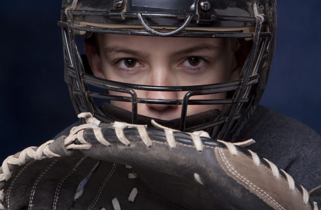 A closeup of a young boy playing baseball and keeping a close eye on the ball with good hand-eye coordination.