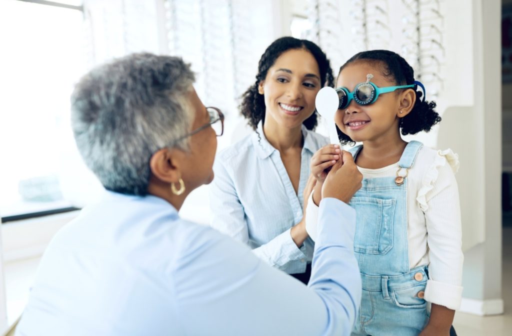 A young girl getting her eyes examined by her pediatric optometrist.