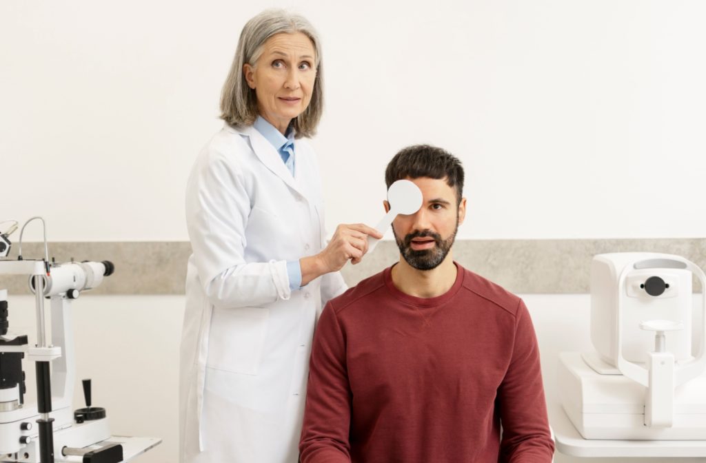 An eye care professional uses an ocular paddle to cover their client's eye during an adult visual training session.