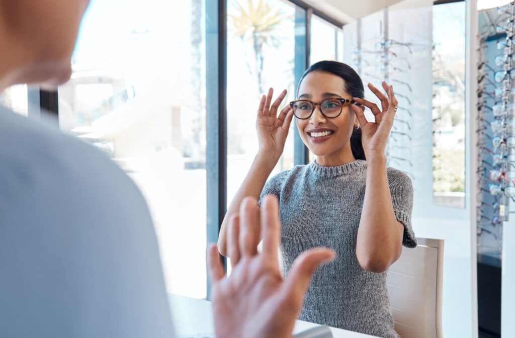 A person visiting the eye doctor and trying on a new pair of glasses with help from an optician