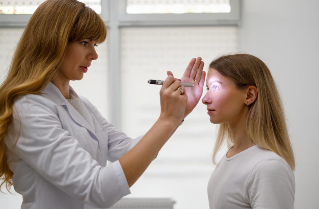 An optometrist shining a light into a persons eye as part of a visual test